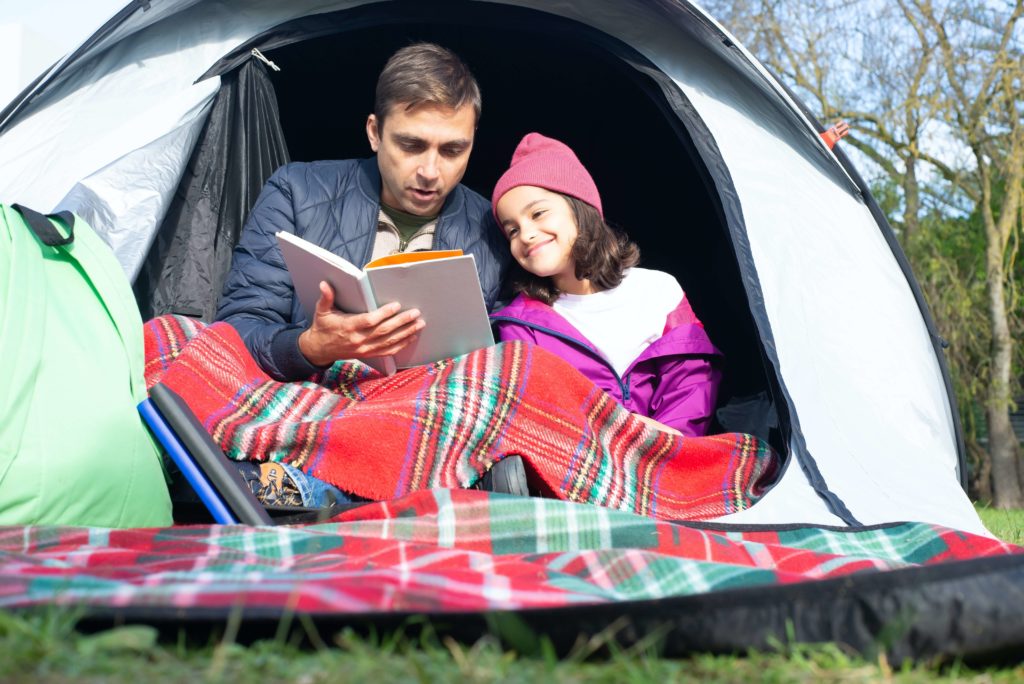 Pour éviter la glissade de l'été, un père et sa fille lisent en camping.